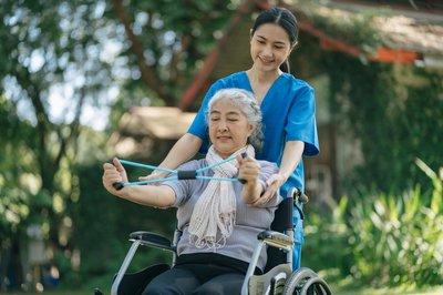 Nurse helping patient in wheelchair with exercise