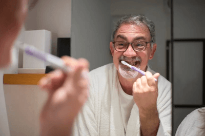 Elderly Man Brushing Teeth in Bathroom