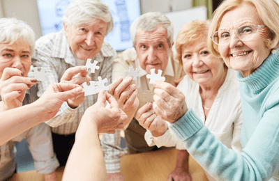 Older adults looking at the camera, holding puzzle pieces.
