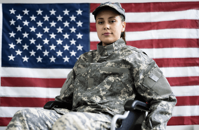 Uniformed service person in a wheelchair with a US flag in the background