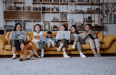 Family Sitting on the Couch while Playing with their Dog