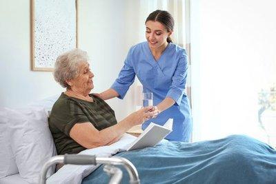 Nurse helping elderly woman in bed