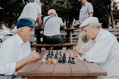 two men playing chess in the park